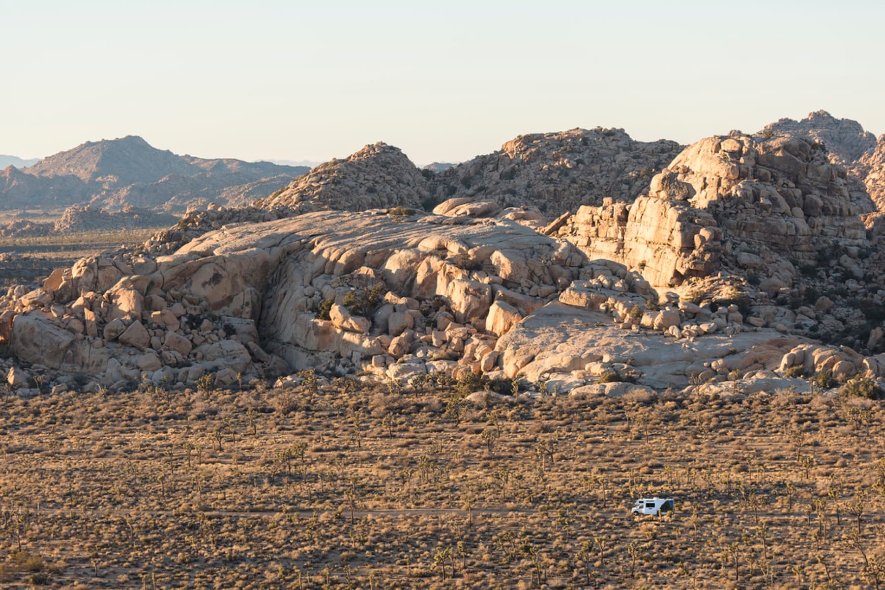 Small RV crossing the desert near rocky outcrops
